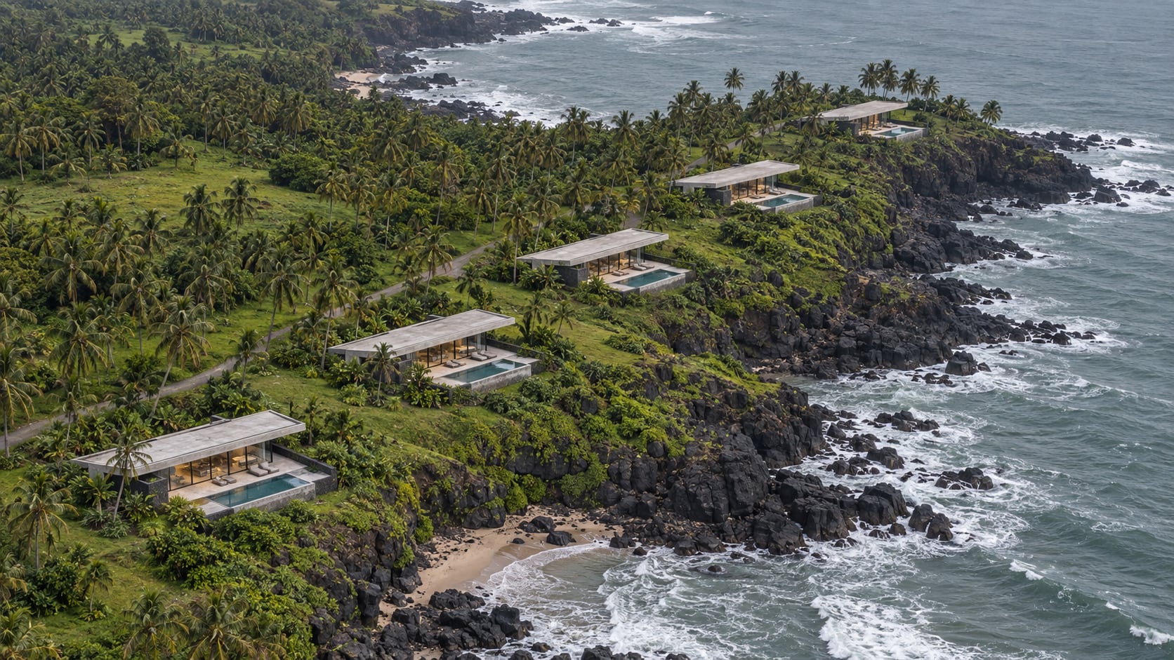 Aerial view of five long concrete houses with pools in a palm grove along a basalt cliff above the sea